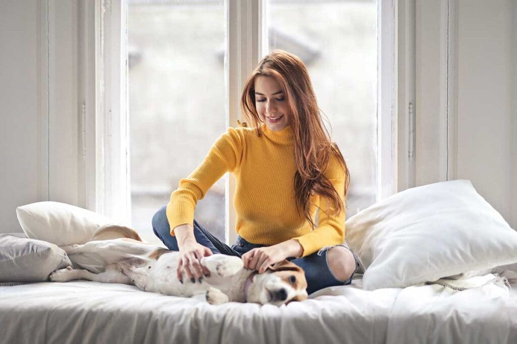 Woman petting her dog in bed
