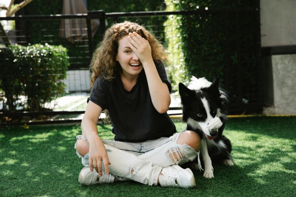 Content woman taming Border Collie on lawn