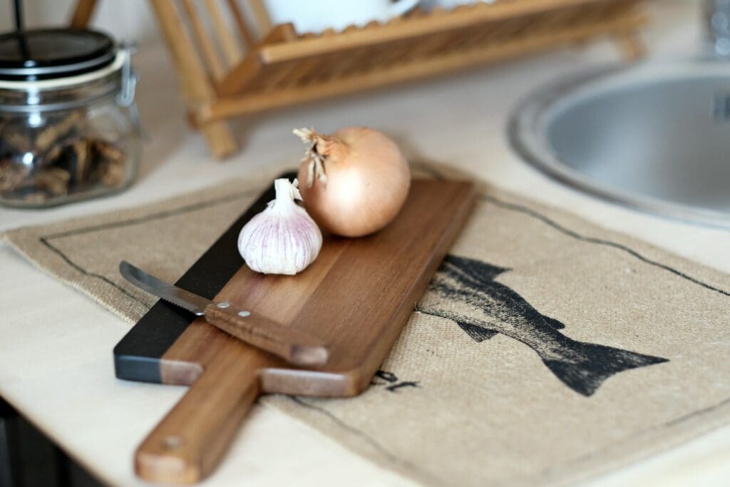 a knife and a garlic and onion bulb on a cutting board