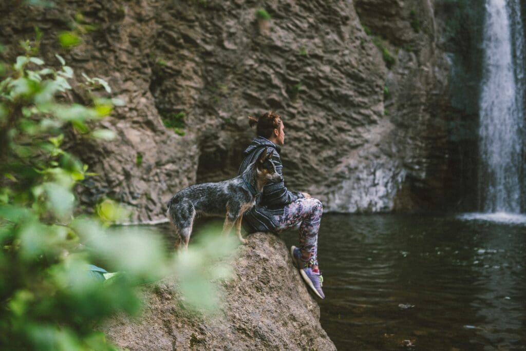 woman in black and white long sleeve shirt and black pants sitting on rock near river