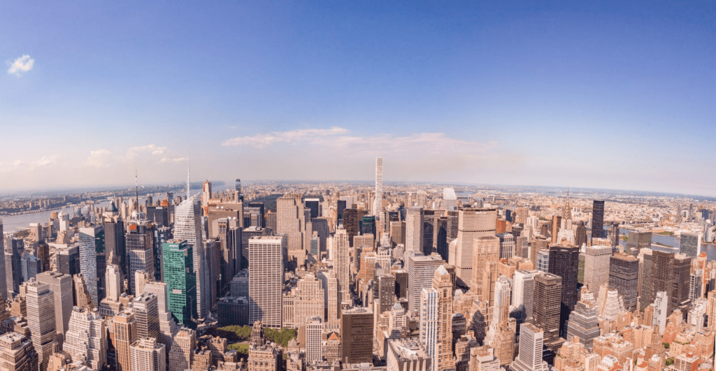 Panoramic aerial view of the iconic New York City skyline featuring skyscrapers and the Hudson River.