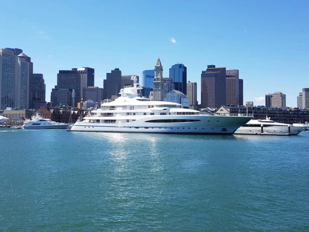A stunning view of a luxury yacht docked in Boston Harbor, framed by the iconic city skyline.