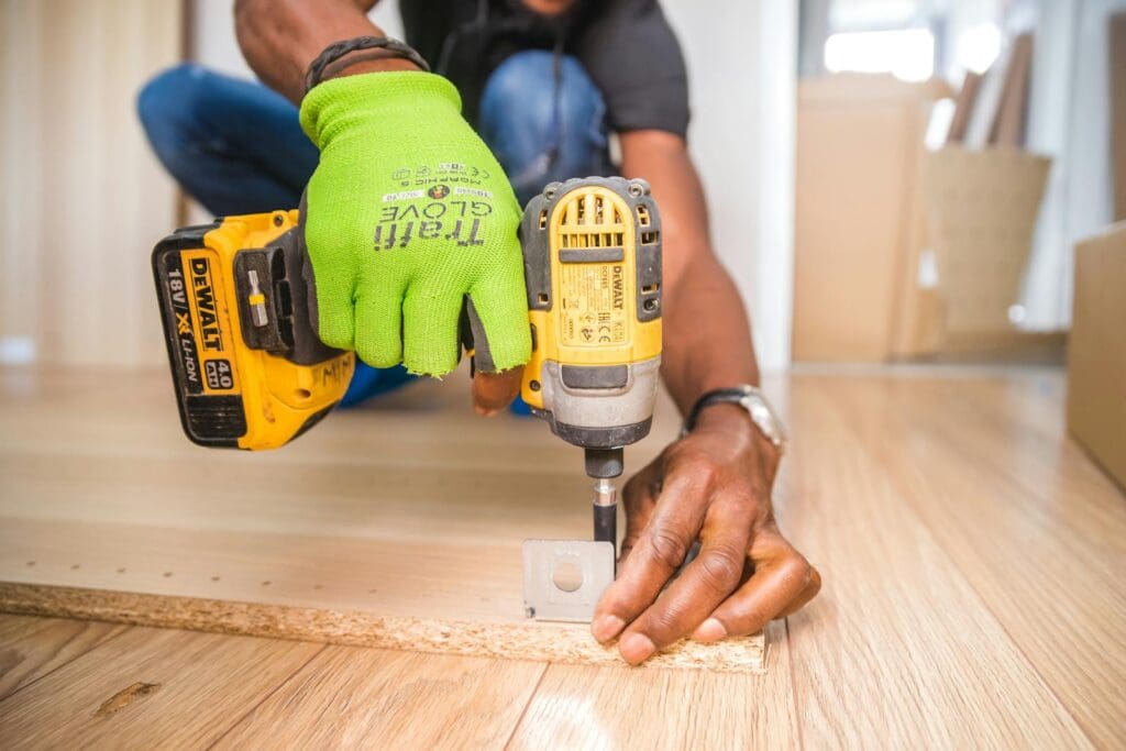 Man using a power drill for home improvement on a wooden floor with precision.,handyman fixing