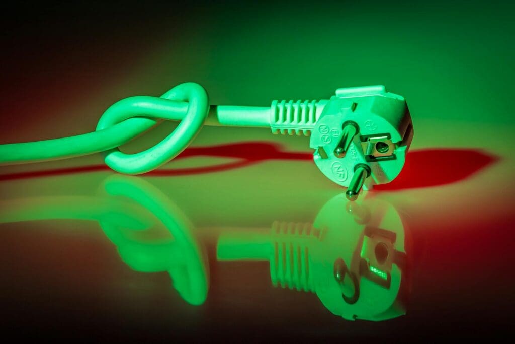 A knotted electrical plug showing reflection with vibrant lighting effects.
