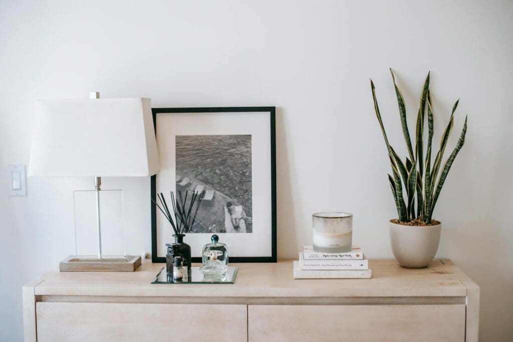 Stylish indoor decoration featuring a plant, candle, and lamp on a chest of drawers.