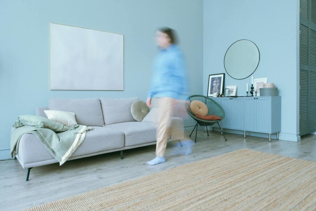 Blurred figure moves in a stylish, minimalist living room with blue accents.