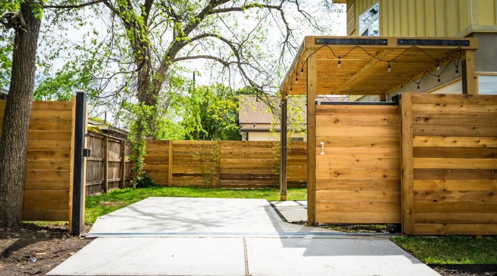 Sunlit wooden fence and patio gate in a peaceful backyard setting.