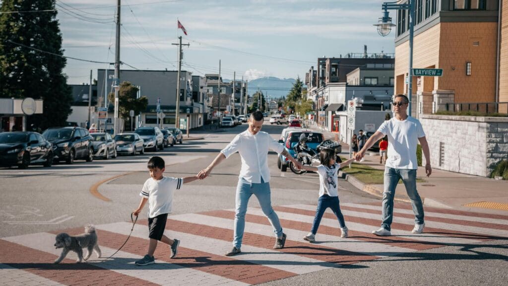 Family with children and dog crossing a pedestrian street on a sunny day in the city.