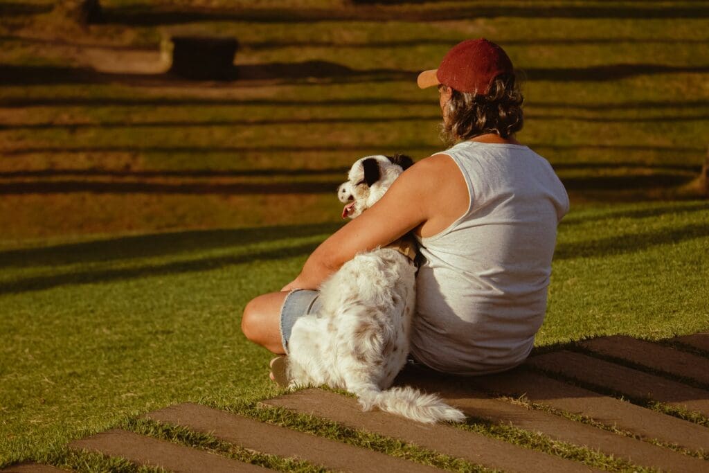 a person and a dog sitting on grass